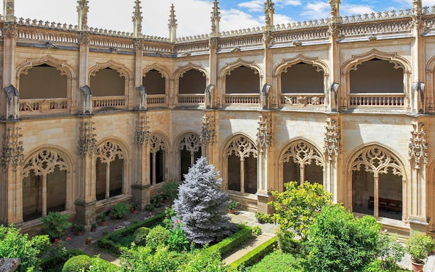 Cloister garden of the Monastery of San Juan de los Reyes, Toledo, with ornate arches.