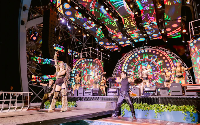 Performers on stage during a vibrant night show on a Dolphin cruise.
