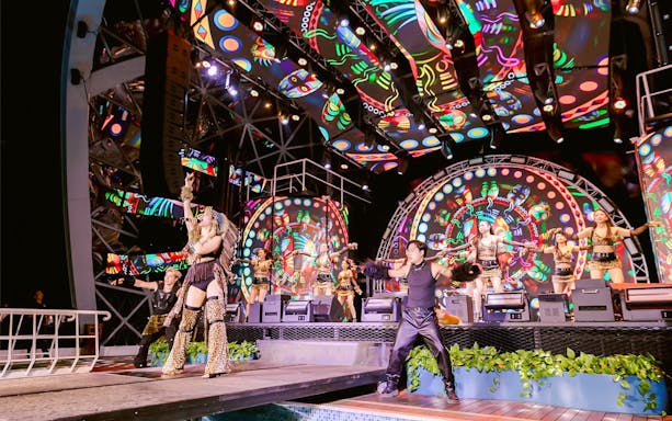 Performers on stage during a vibrant night show on a Dolphin cruise.