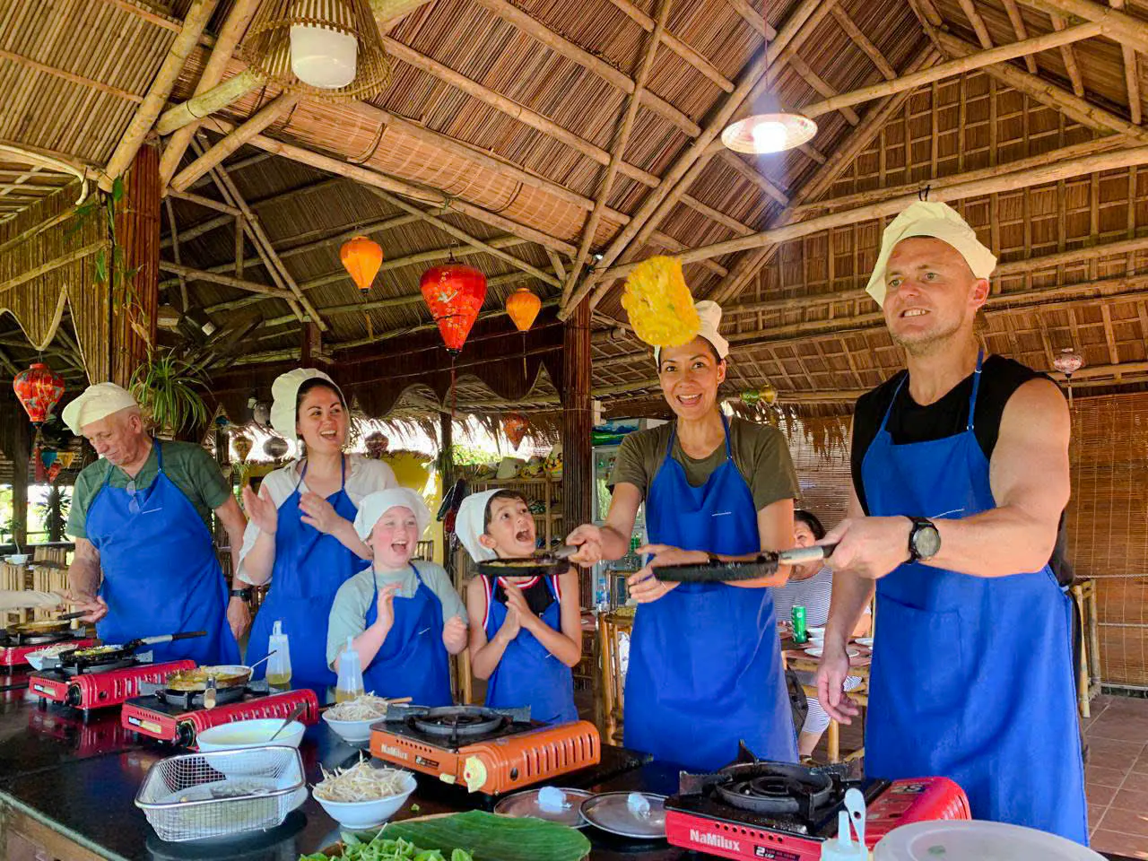 Cooking class in Hoi An with participants flipping pancakes, part of the 3 Heritage Craft Villages Tour.