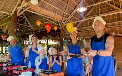 Cooking class in Hoi An with participants flipping pancakes, part of the 3 Heritage Craft Villages Tour.