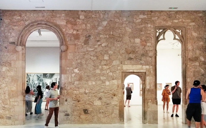 Visitors exploring exhibits at Picasso Museum Barcelona through stone archways.