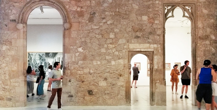 Visitors exploring exhibits at Picasso Museum Barcelona through stone archways.