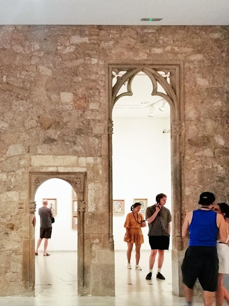 Visitors exploring exhibits at Picasso Museum Barcelona through stone archways.