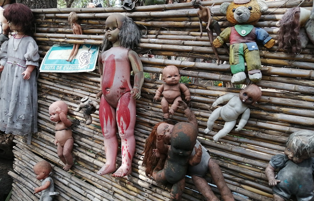 Xochimilco Island of Dolls canal with colorful boats and hanging dolls in Mexico City.