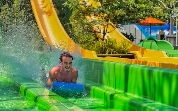Man sliding down a colorful water slide at Waterbom Bali.
