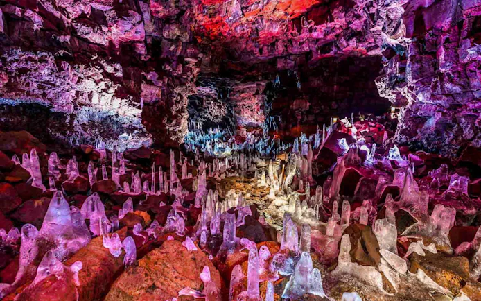 Raufarhólshellir Lava Tunnel interior with colorful rock formations and ice stalagmites.