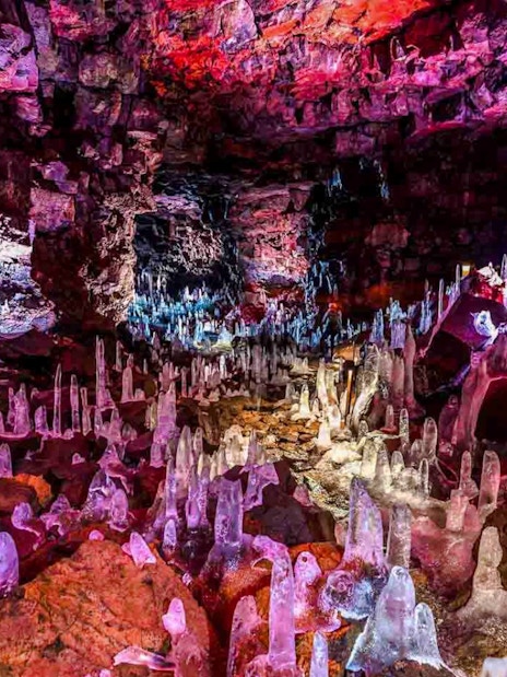 Raufarhólshellir Lava Tunnel interior with colorful rock formations and ice stalagmites.