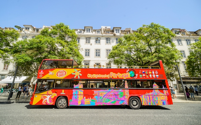 Hop-On Hop-Off Lisbon tour bus in front of historic Lisbon buildings.