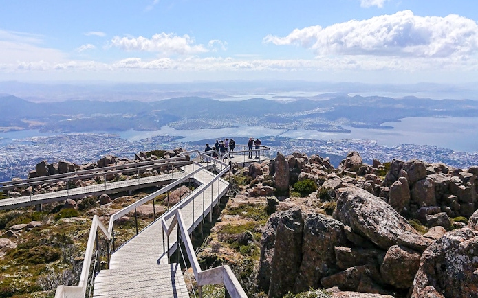 Kunanyi Mt Wellington view with visitors on boardwalk overlooking Hobart, Tasmania.