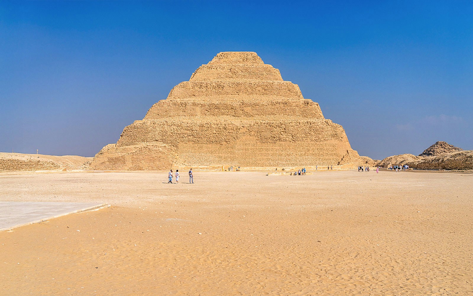 Step Pyramid of Djoser at Saqqara near Cairo, Egypt with visitors exploring.