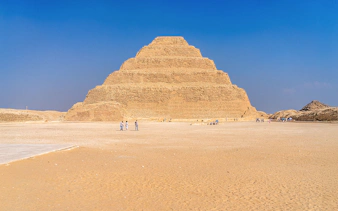 Step Pyramid of Djoser at Saqqara near Cairo, Egypt with visitors exploring.