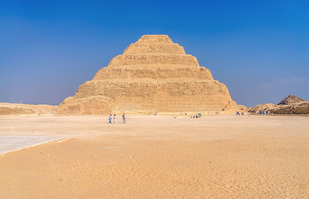 Step Pyramid of Djoser at Saqqara near Cairo, Egypt with visitors exploring.