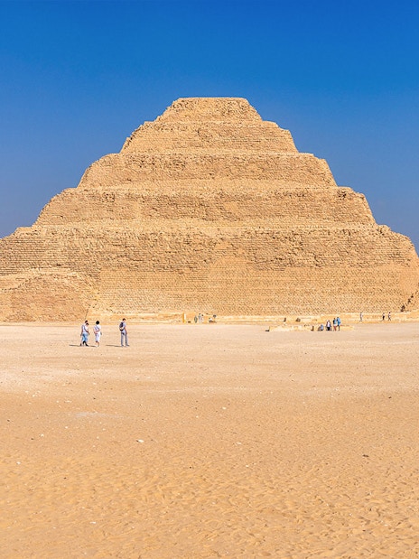 Step Pyramid of Djoser at Saqqara near Cairo, Egypt with visitors exploring.