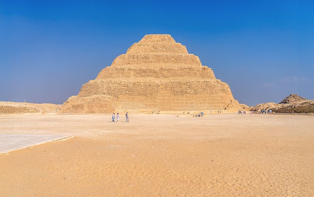 Step Pyramid of Djoser at Saqqara near Cairo, Egypt with visitors exploring.