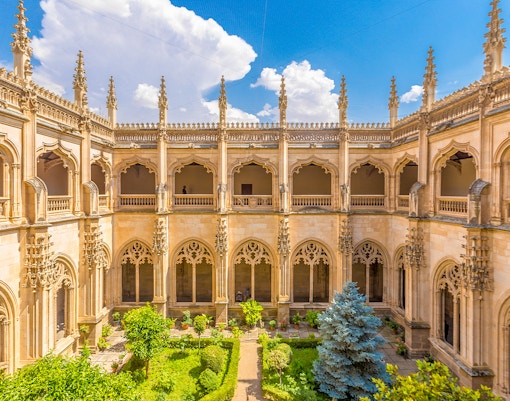 Cloister of Monasterio de San Juan de los Reyes in Toledo, Spain, with Gothic arches and garden.
