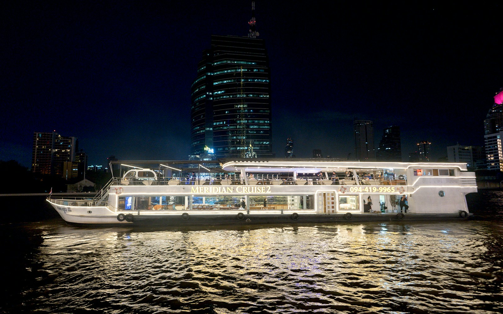 Chao Phraya River view from Meridian Cruise in Bangkok with illuminated cityscape.