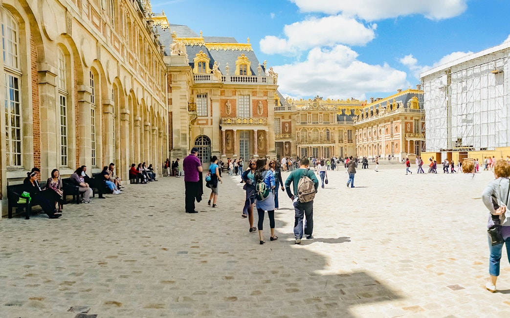 Tourists walking in the courtyard of Versailles Palace, France.