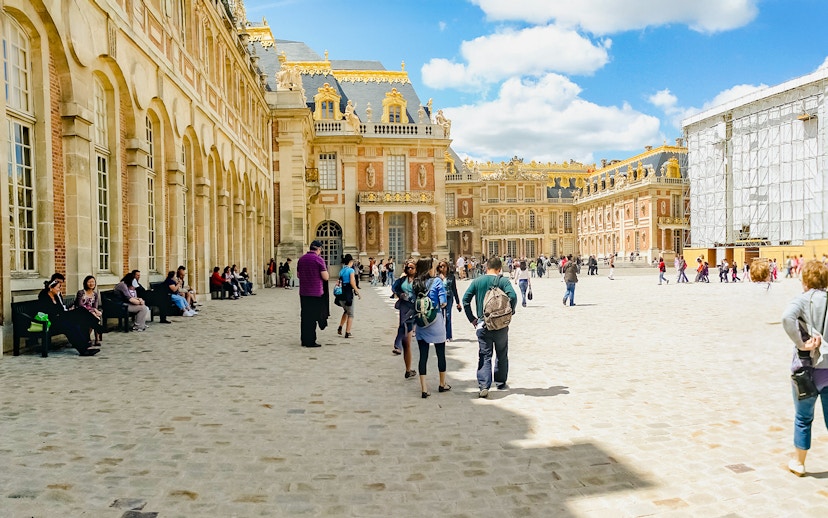 Tourists walking in the courtyard of Versailles Palace, France.