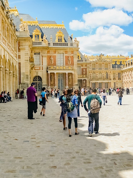 Tourists walking in the courtyard of Versailles Palace, France.