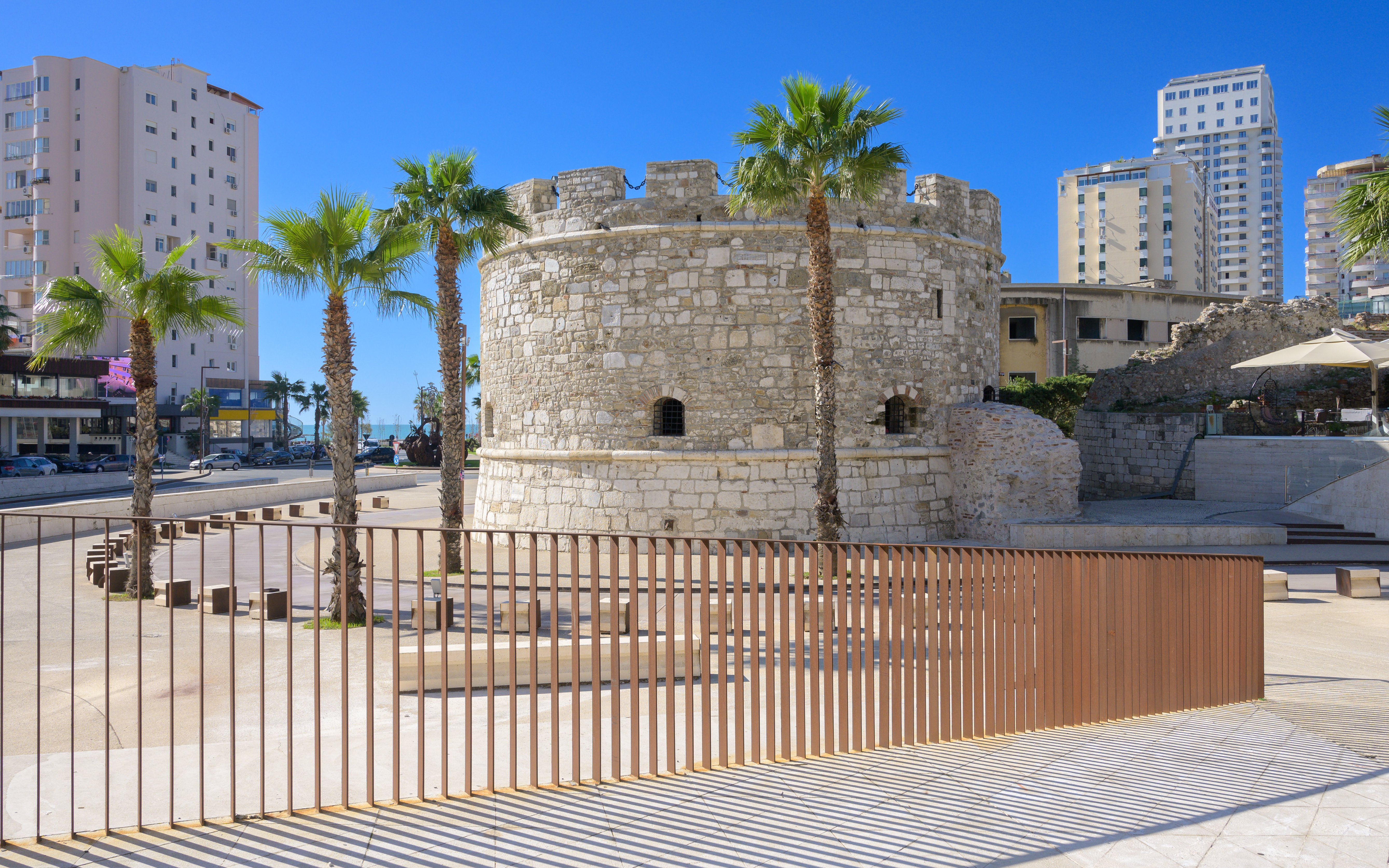 Venetian Tower of Durres with palm trees and modern buildings in the background, Albania.
