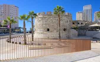 Venetian Tower of Durres with palm trees and modern buildings in the background, Albania.