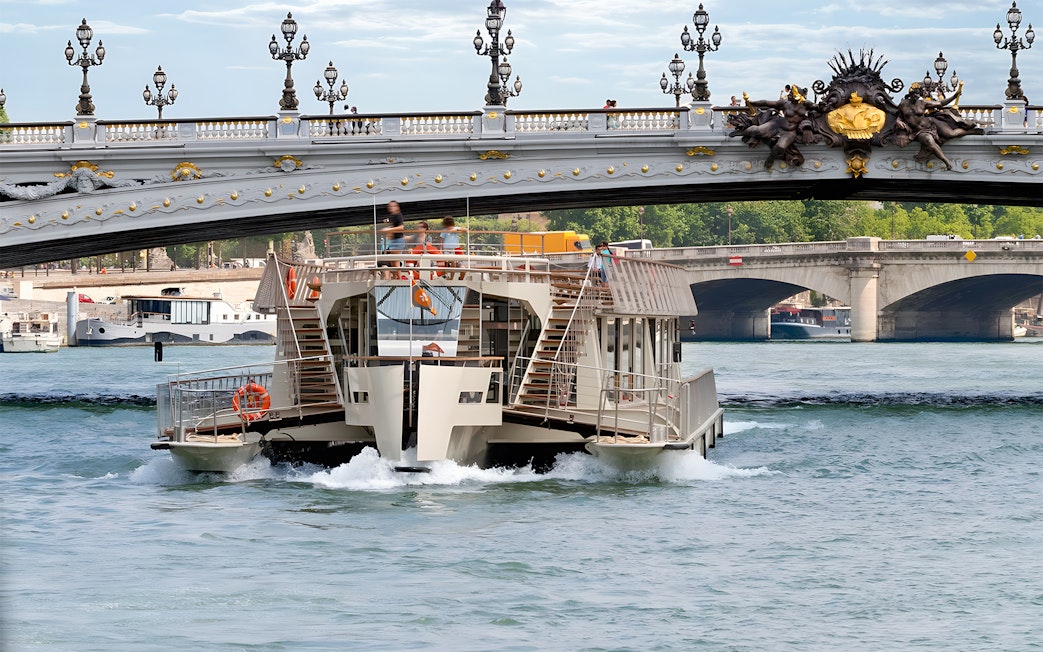 Seine River cruise boat passing under Pont Alexandre III in Paris.
