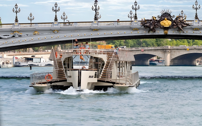 Seine River cruise boat passing under Pont Alexandre III in Paris.