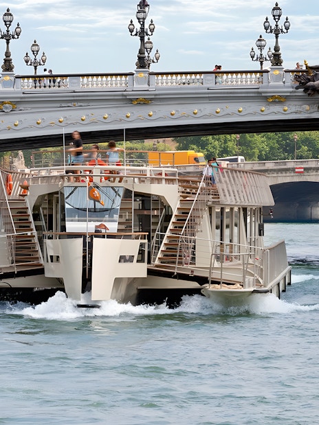 Seine River cruise boat passing under Pont Alexandre III in Paris.