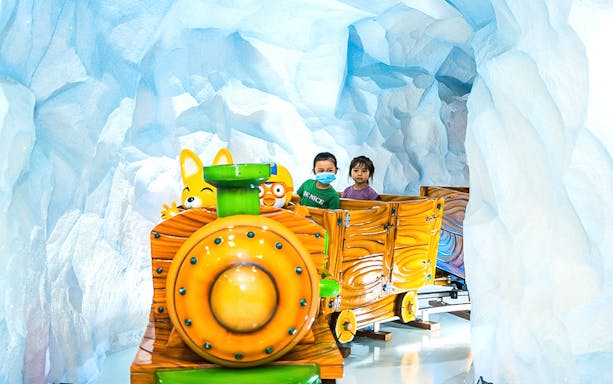 Children riding a themed train through icy cave at Pororo Park Singapore.