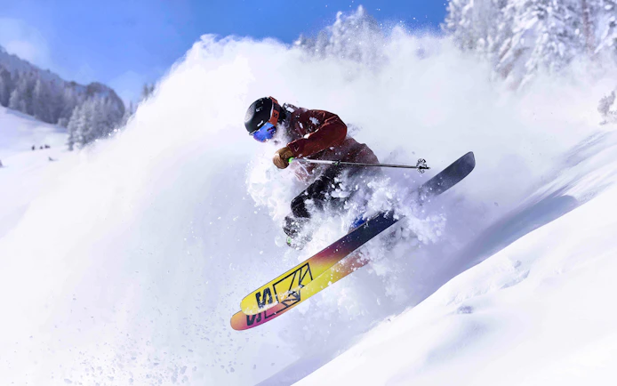 Skier navigating powder snow on a mountain slope, Ikon Pass multi-resort access.