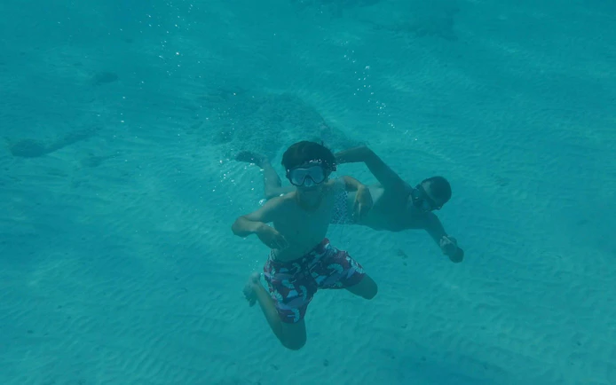 Tourists swimming underwater during a sunset cruise.