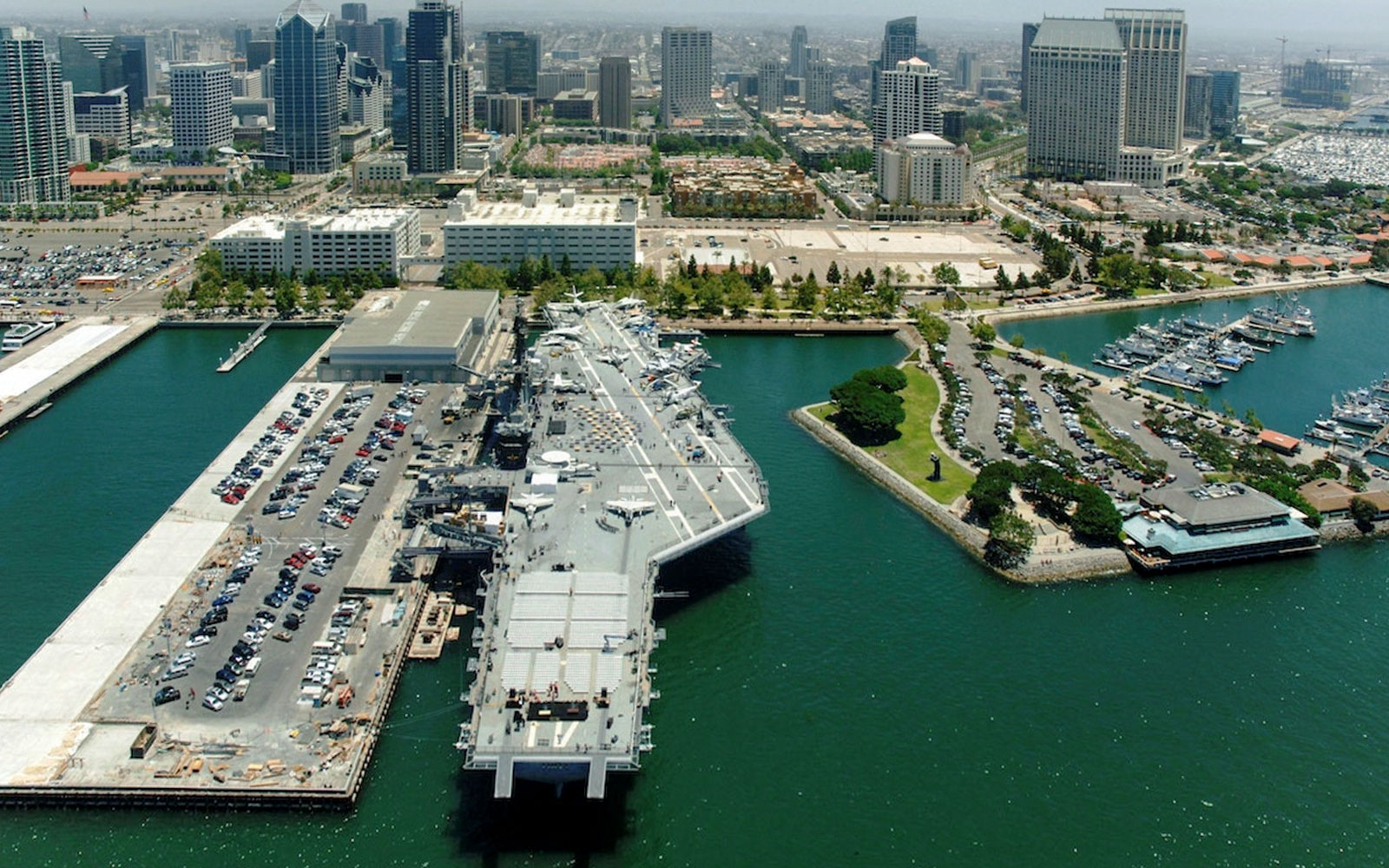 USS Midway Museum aircraft carrier docked in San Diego harbor with city skyline.