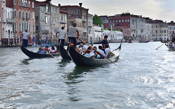 Gondolas with passengers on Venice canal during serenade tour.