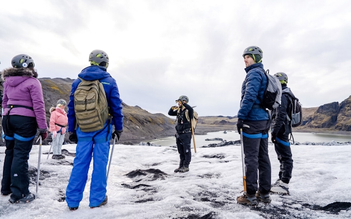 Guests hiking on Sólheimajökull glacier with guide in Iceland.