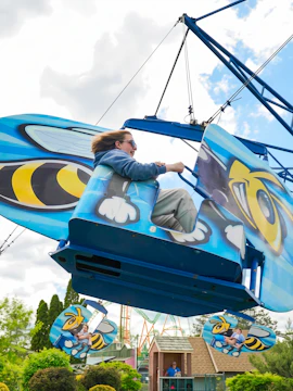 Person enjoying Hornet's Nest ride at Six Flags Darien Lake, featuring bee-themed design.