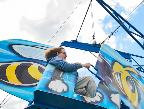 Person enjoying Hornet's Nest ride at Six Flags Darien Lake, featuring bee-themed design.
