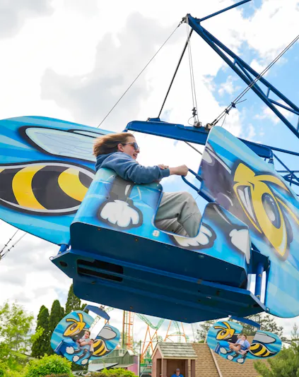 Person enjoying Hornet's Nest ride at Six Flags Darien Lake, featuring bee-themed design.