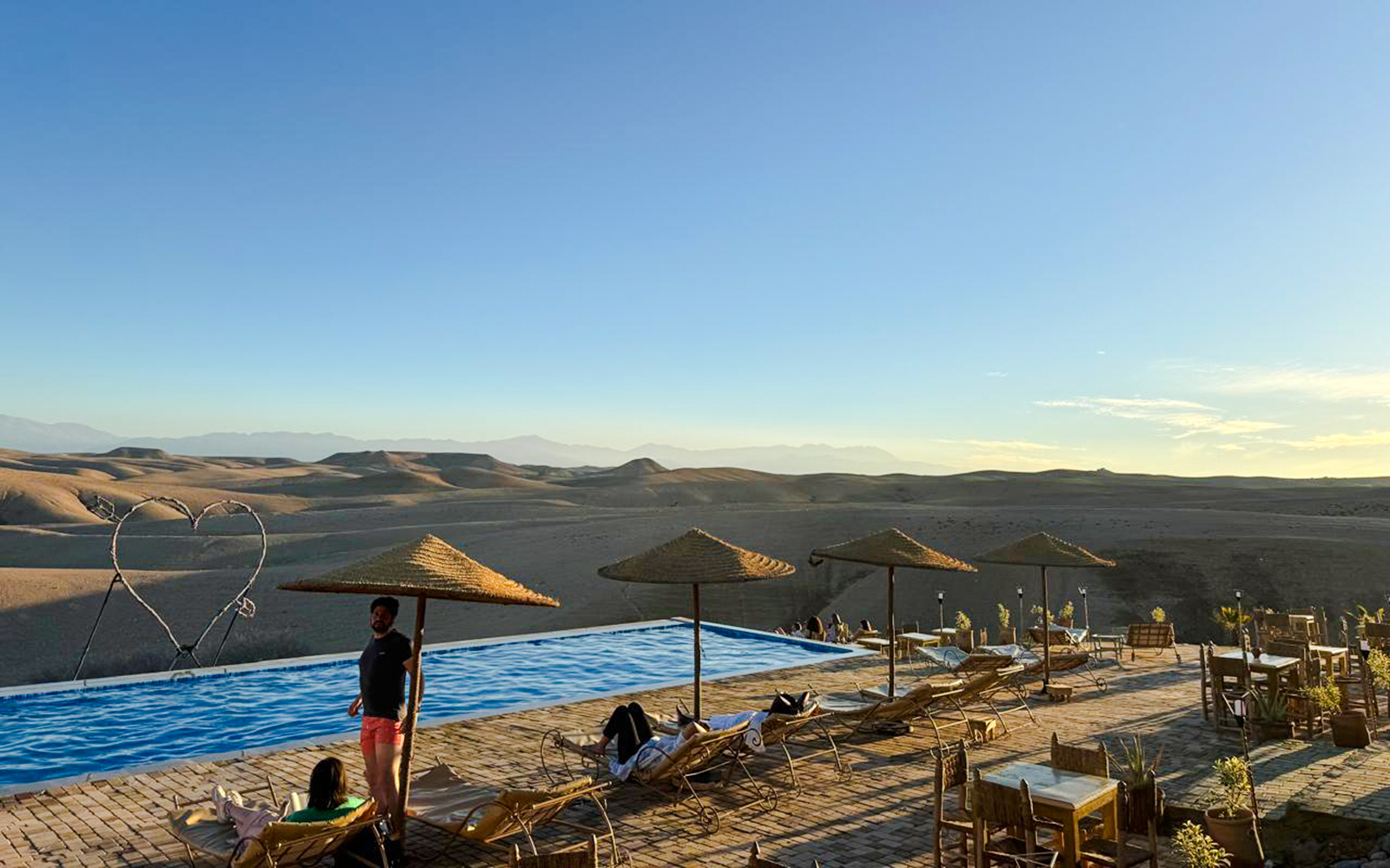 Infinity pool overlooking Agafay desert with lounge chairs and parasols in Marrakesh.