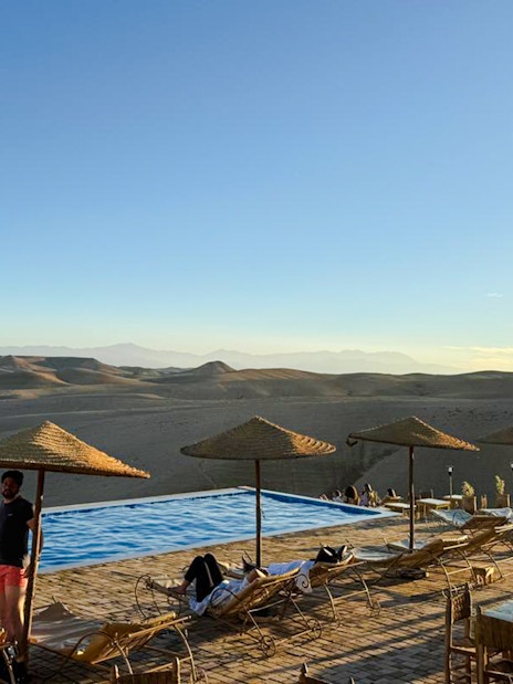 Infinity pool overlooking Agafay desert with lounge chairs and parasols in Marrakesh.