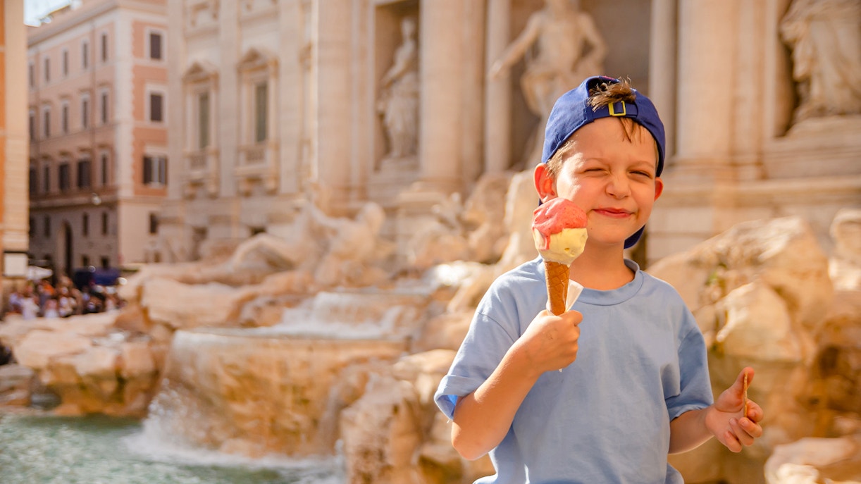 Boy enjoying gelato at Trevi Fountain, Rome.