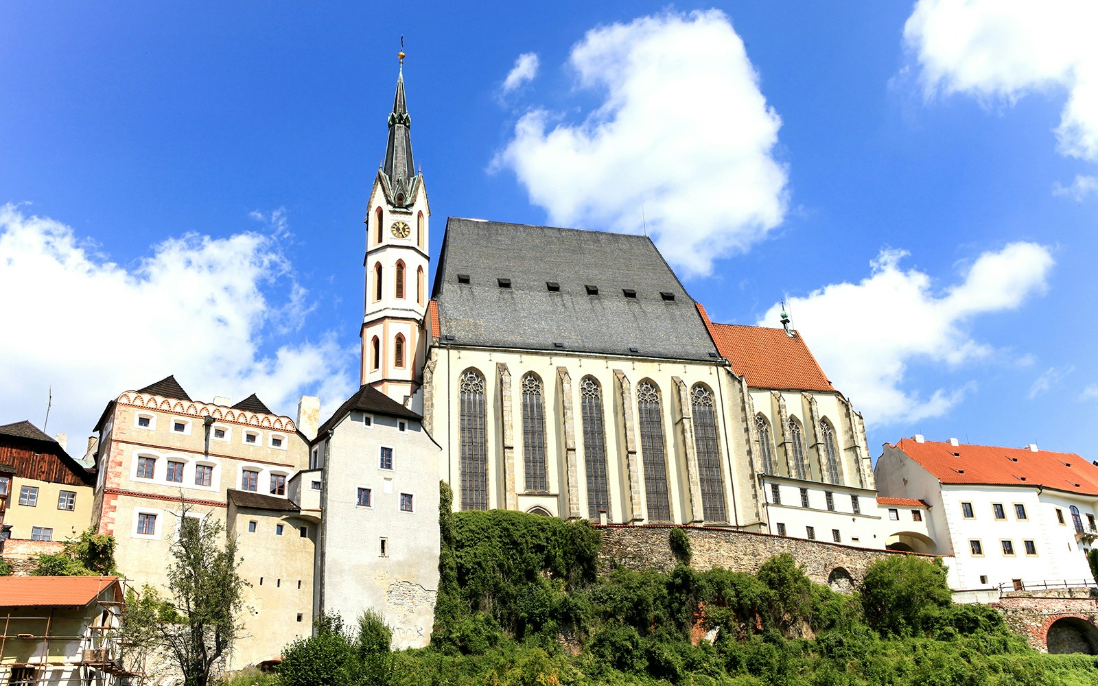 Saint Vitus church exterior in Cesky Krumlov with Gothic architecture and surrounding greenery.
