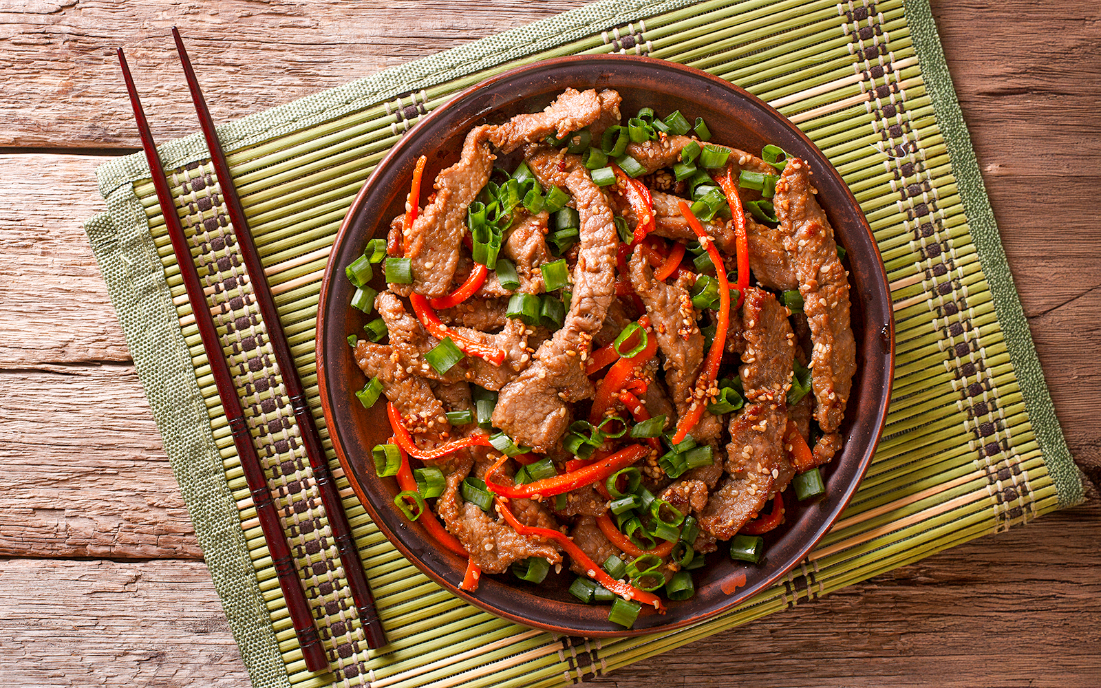 Bulgogi beef slices with sesame on a plate, showcasing Korean cuisine.