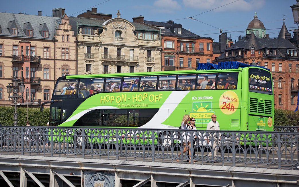 Hop-on hop-off bus in Stockholm with historic buildings in the background.