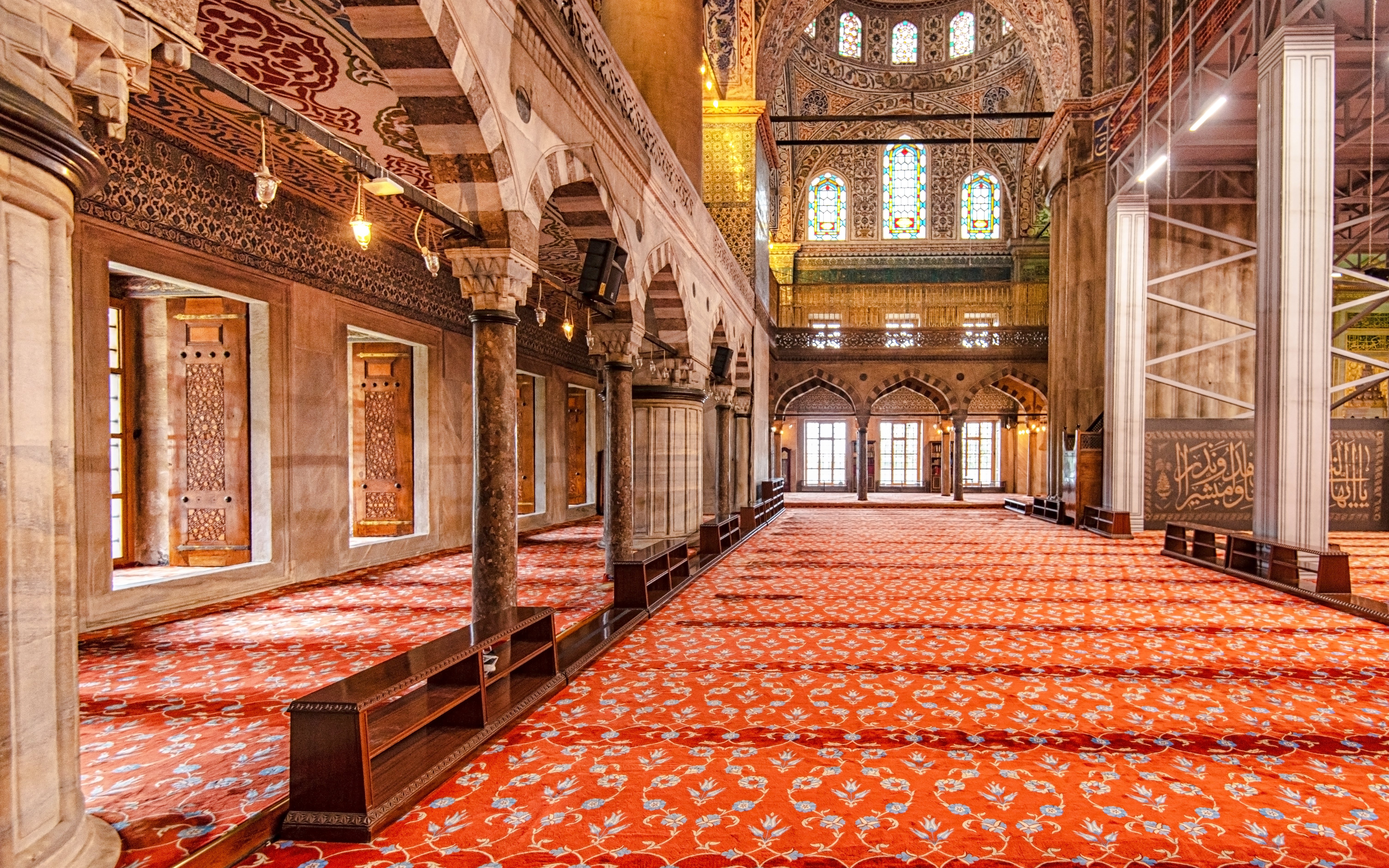 Interior view of the Blue Mosque in Istanbul with ornate arches and patterned carpet.