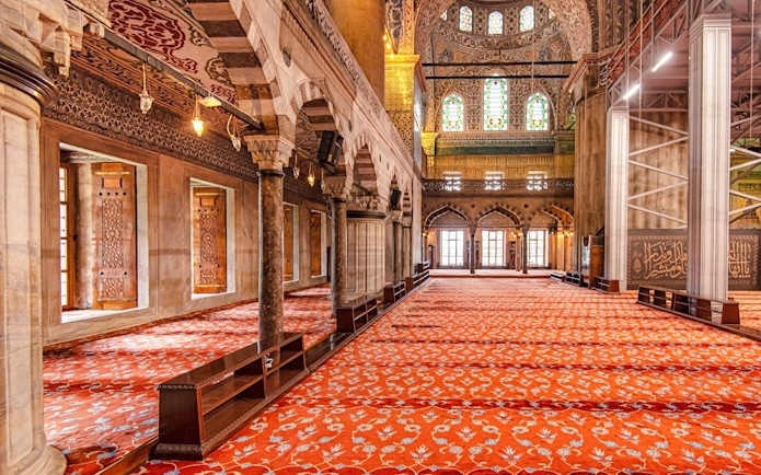 Interior view of the Blue Mosque in Istanbul with ornate arches and patterned carpet.