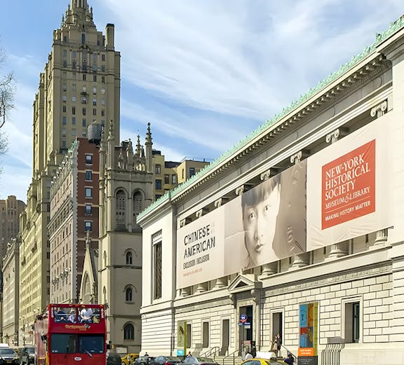 New York Historical Society building with exhibition banners and city street.