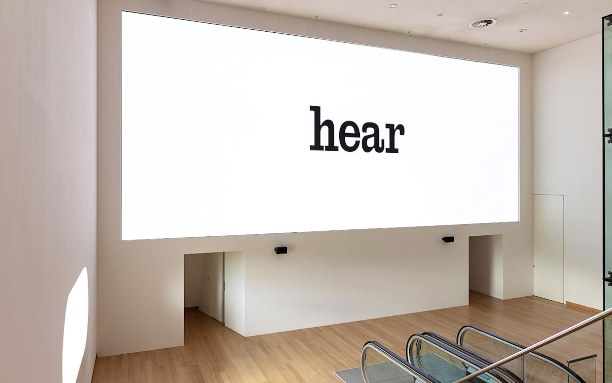 Installation view of IN SITU 1 Exhibit at Stedelijk Museum with "hear" text on wall.