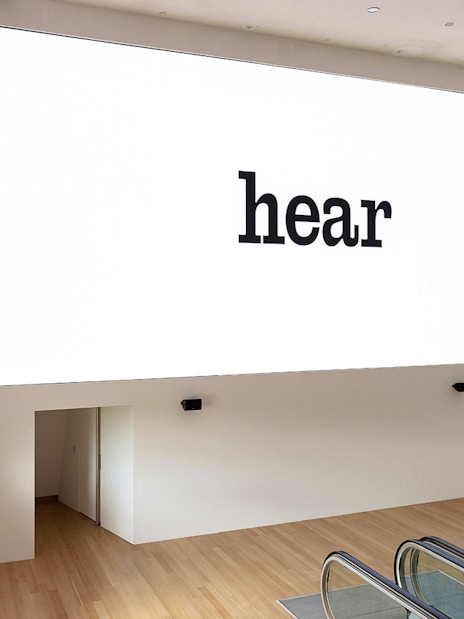 Installation view of IN SITU 1 Exhibit at Stedelijk Museum with "hear" text on wall.