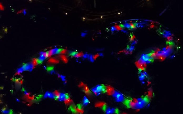 Neon-lit luge track winding through a dark landscape at night.